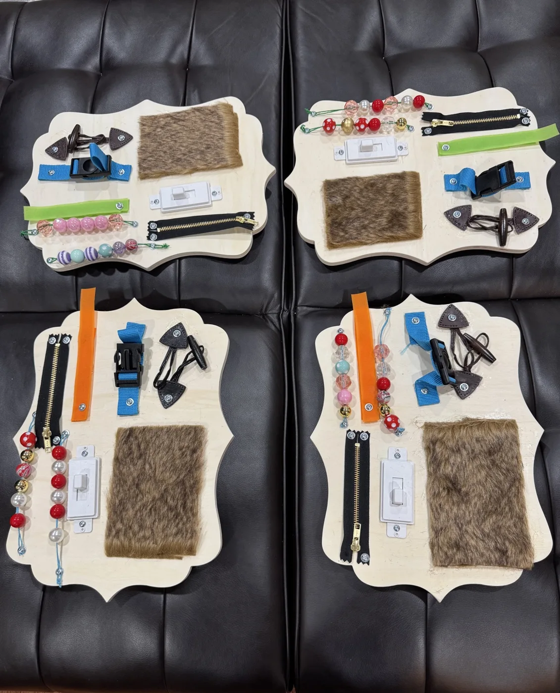 All four finished boards laid out, each carrying zippers, buckles, light switches, beads and fur patches