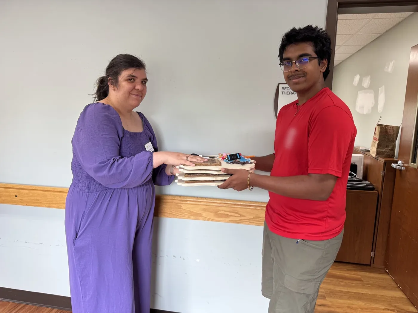Me handing the stack of finished boards to a staff member in a facility corridor